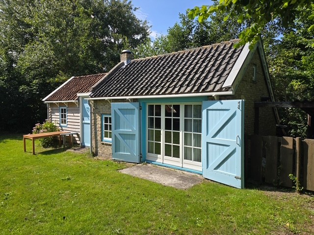 Zijkant van het bakstenen huisje met houten gevel