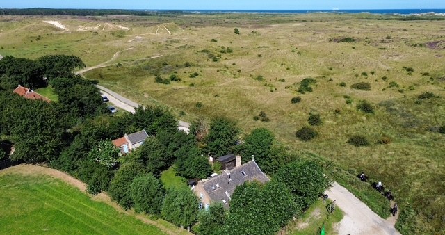 Luchtfoto van het huisje naast het duinlandschap
